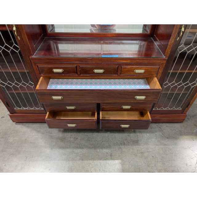 Solid mahogany entertainment wall unit with two tall diamond-leaded display cabinets flanking a mirrored center bay over...