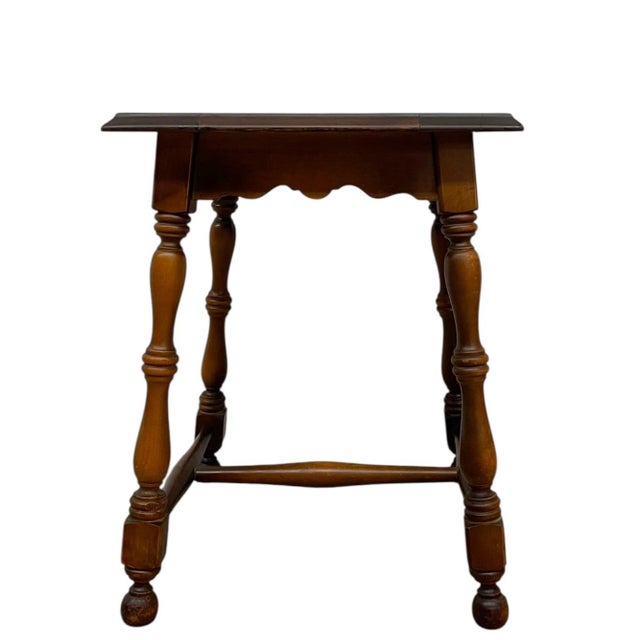 This vintage side table features a square wood frame inset with a decorative ceramic tile top, showcasing a bold,...