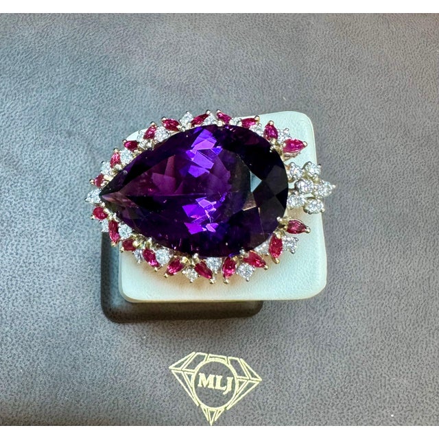 Introducing a timeless cocktail ring featuring a stunning 50 Ct measuring 32 X 23 Pear-shaped Amethyst and diamond with...
