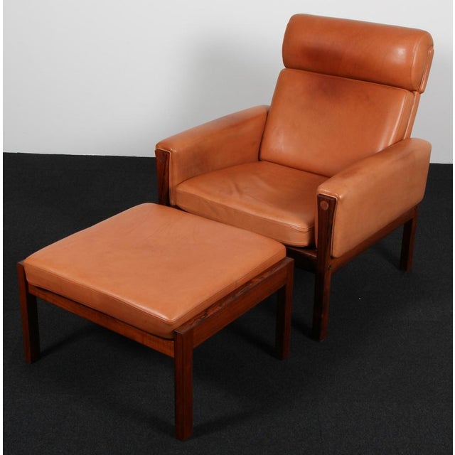 Hans j. Wegner lounge chair and ottoman, upholstered with patinated cognac leather. Frame of rossewood. Model ap 62, made...