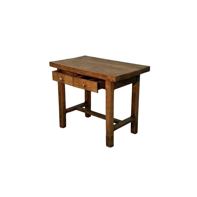 A small 19th-century walnut writing table, featuring a thick top that emphasizes its solidity and rustic character. The...