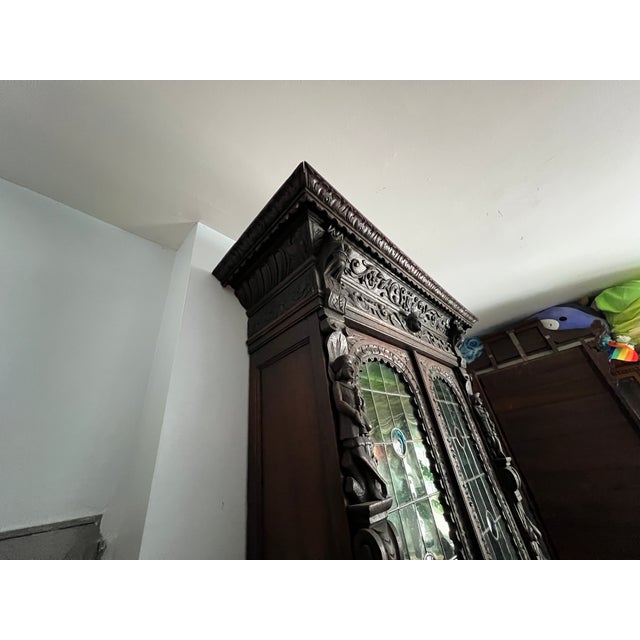 Dated to the late 1800s, this two-piece cabinet is treated with innumerable, heavily carved details for an eye-catching...