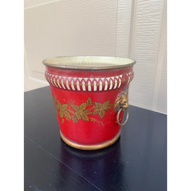 A wonderfully charming early 20th century French tole cachepot finished in a rich cinnabar red with delicate gilt...