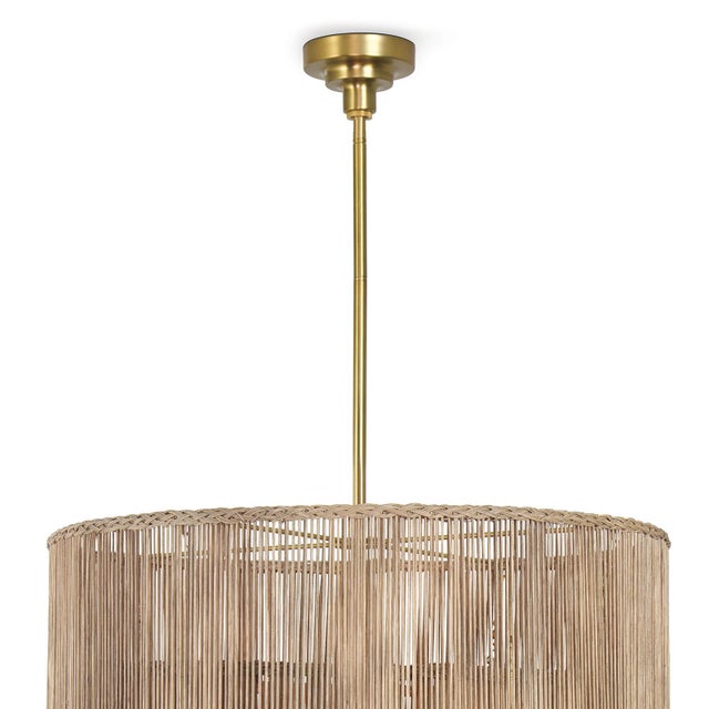 Three layers of woven drum shades with braided edges tier upwards, concealing a double bulb torch design in natural brass...