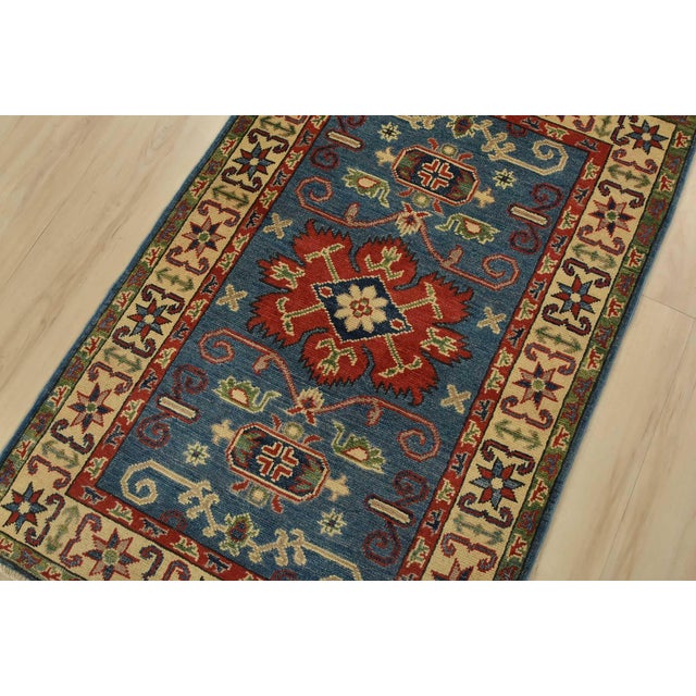 A tribal Caucasian Kazak rug hand-knotted with fine wool on a cotton foundation. This rug features a central medallion...