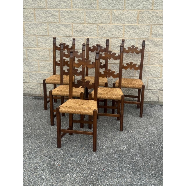 Set of six vintage Italian dining chairs featuring tall carved wood frames with decorative pierced backs and woven rush...