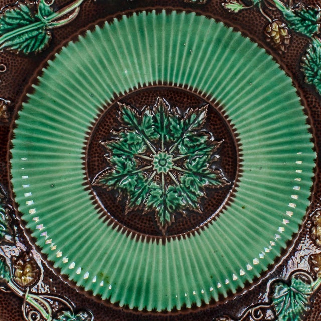 A 19th century English George Jones Majolica glazed ceramic plate with grapevine pattern in green and brown, center...