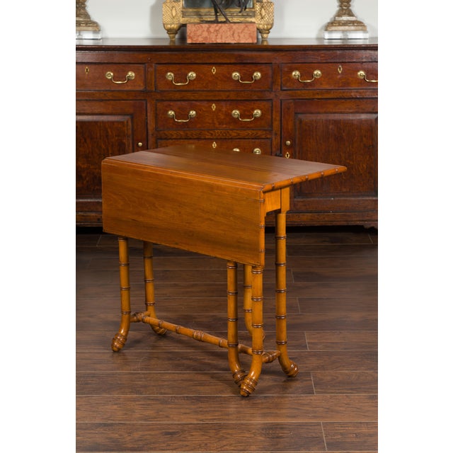 An English walnut drop-leaf table from the early 20th century, with faux-bamboo base. Created in England during the early...