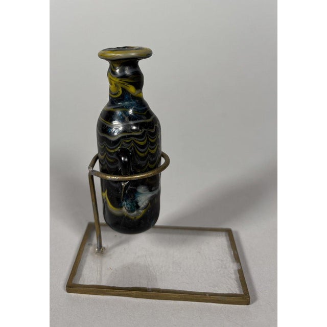 Phoenician Amphorisco, 2nd-1st Century BC. Amphorisco made of blue glass paste, with a cylindrical body and a cylindrical...