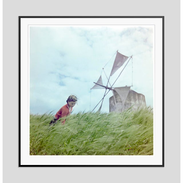 A Windmill In Portugal by Toni Frissell A woman takes a break in a wheat field next to an old windmill, Portugal 1946....