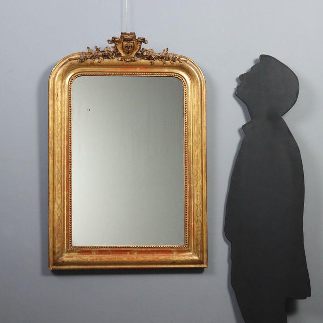 A carved and gilded wooden mirror dating back to the late 19th century, from Italy. The frame features a richly crafted...