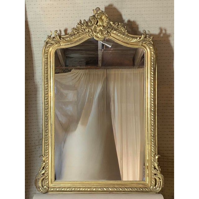 A beautifully gilded wall or pier mirror of elegant form, the graceful curves of the crest are complemented by the Rococo...