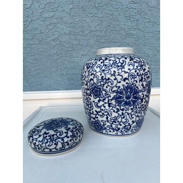 Late 20th Century decorative blue and white ceramic ginger jar. It has a chinoiserie floral and vine motif. The jar and...