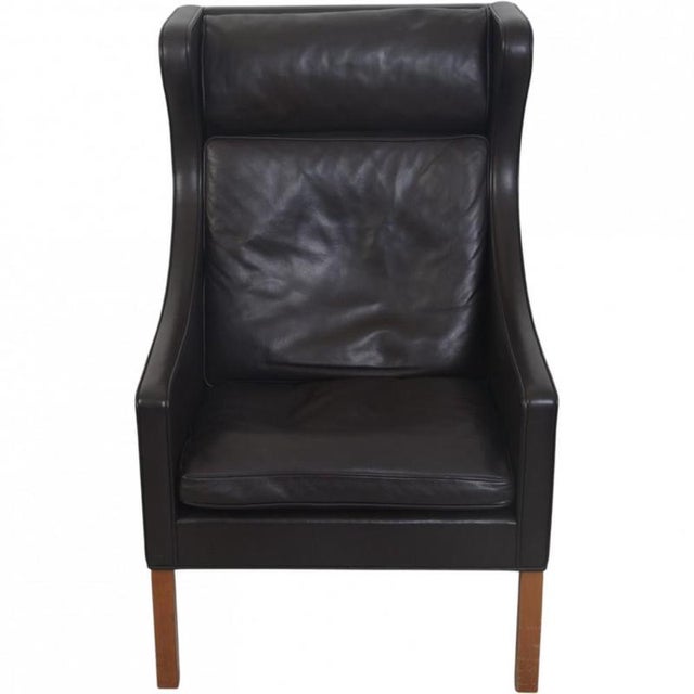 Børge Mogensen wing chair with stool, model 2204, upholstered in black leather and with legs of mahogany. The chair is...