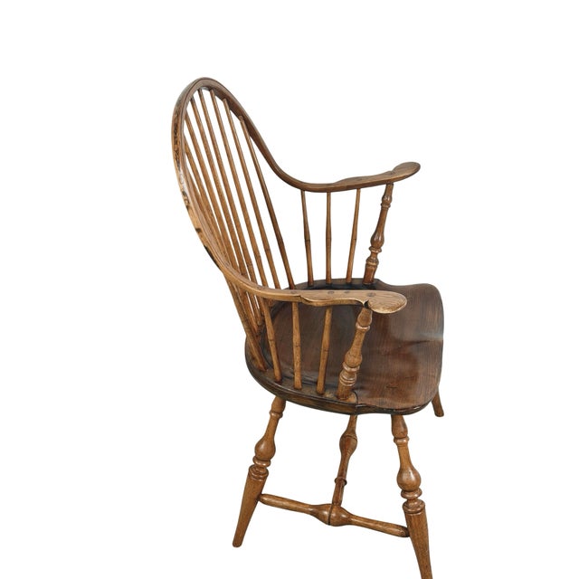 A handsome antique Windsor armchair featuring a tall, gracefully arched continuous bow-back, slender turned spindles, and...