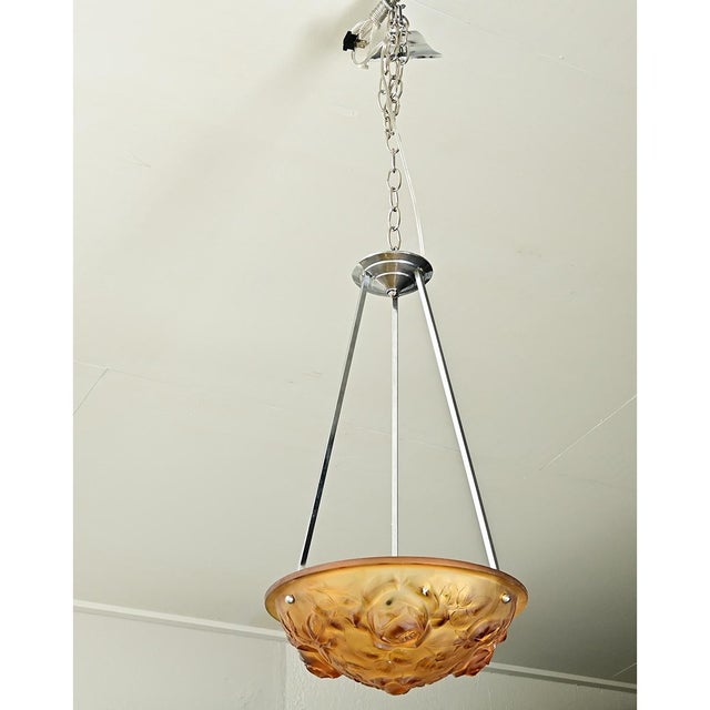 This French Art Deco chandelier (early 20th century) has a frosted, amber-glass diffuser with textural roses and foliate...