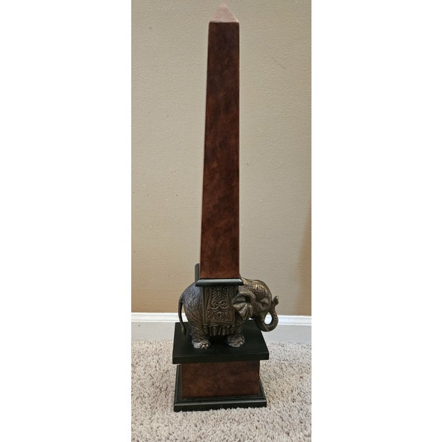 A lovely vintage wood obelisk resting on a metal elephant's back, resting on a wooden plinth. The trunk is 'up' which...
