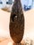 Design and Visual CharacteristicsForm: The sculpture features a sleek, vertically elongated surfboard- or shield-like...