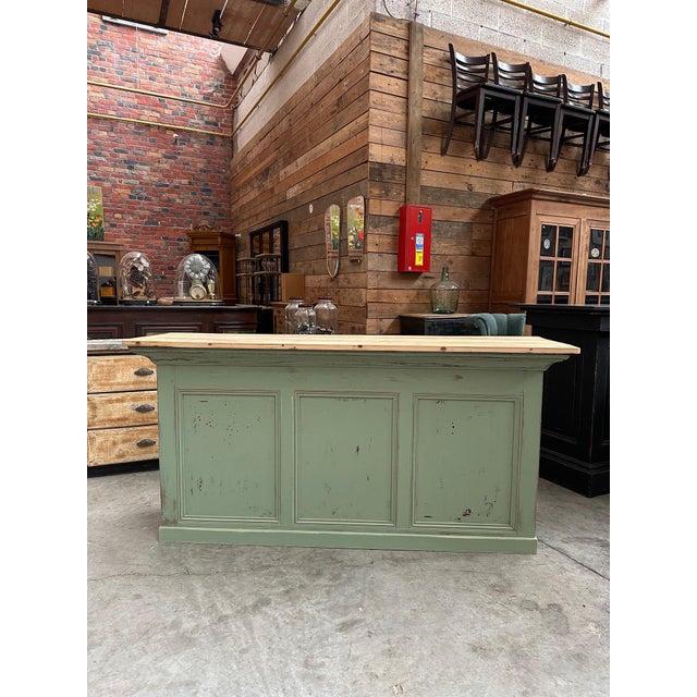 This old shop counter has been completely restored. Its body has a green patina finish and its top is made of raw wood. At...