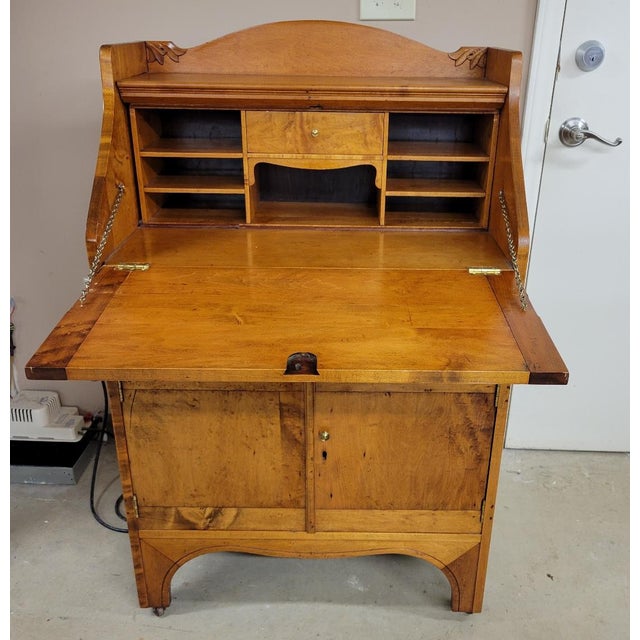 A finely proportioned American slant-front secretary desk crafted in solid maple, featuring restrained carved detailing...