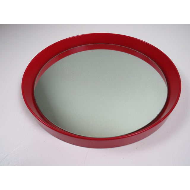 This mid-century modern circular wall mirror features a bold red lacquered wooden frame with a gently raised profile. The...