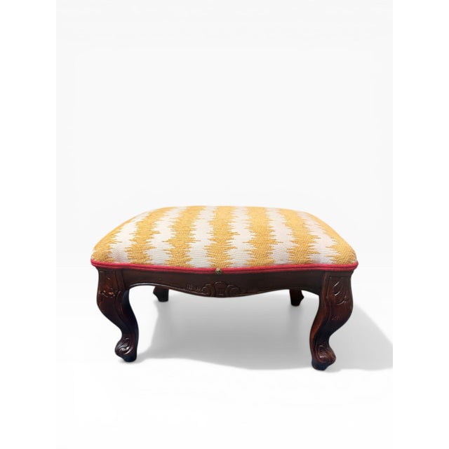A charming vintage carved wood footstool featuring a richly toned wood frame with graceful cabriole legs and subtle...