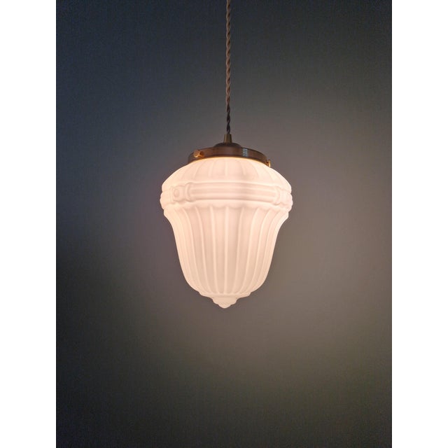 Art Deco pendant light in pressed molded white glass (milk glass) with a brass mount, 1920s-30s. The pendant light has...