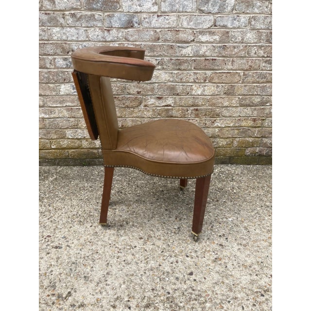 Beautiful English cock fighting chair with folding writing tablet in original leather and with brass sabots and casters.