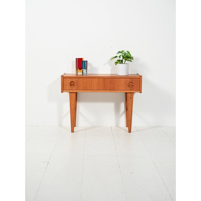 1950s Scandinavian teak and oak nightstand with one drawer, a decorative carved handle, and tapered legs. A 1950s...