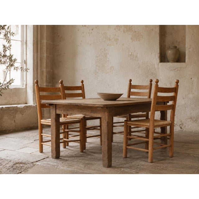 A characterful set of four French rustic dining chairs, dating from approximately the 1950s or 1960s. The chairs feature...