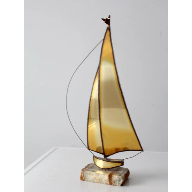This Jere Demott sailboat sculpture is a striking piece of art, featuring patinated brass sheets and copper wire with a...