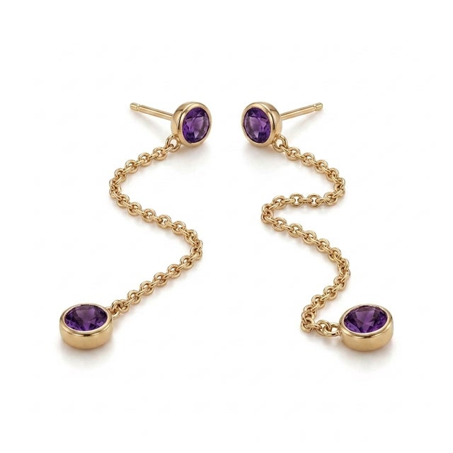 The earrings are adorned with vibrant, round-cut natural amethyst gemstones that exhibit deep, royal purple hues. The...