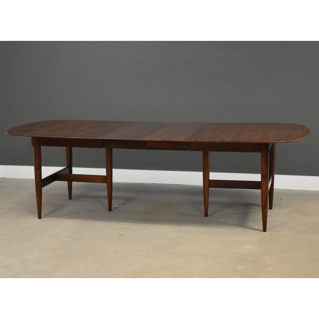 A mid century modern solid Cherry oval dining table made by Willett Furniture with two 14.125” leaves which fully extend...