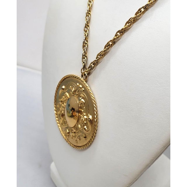 This is part of Chairish’s Costume Jewelry assortment. 1960s Baroque style goldtone round repoussé with oval domed center...