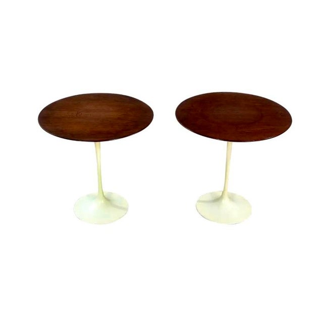 A pair of 1960's iconic walnut tulip tables designed by Eero Saarinen for Knoll. The tabletops are supported by heavy cast...