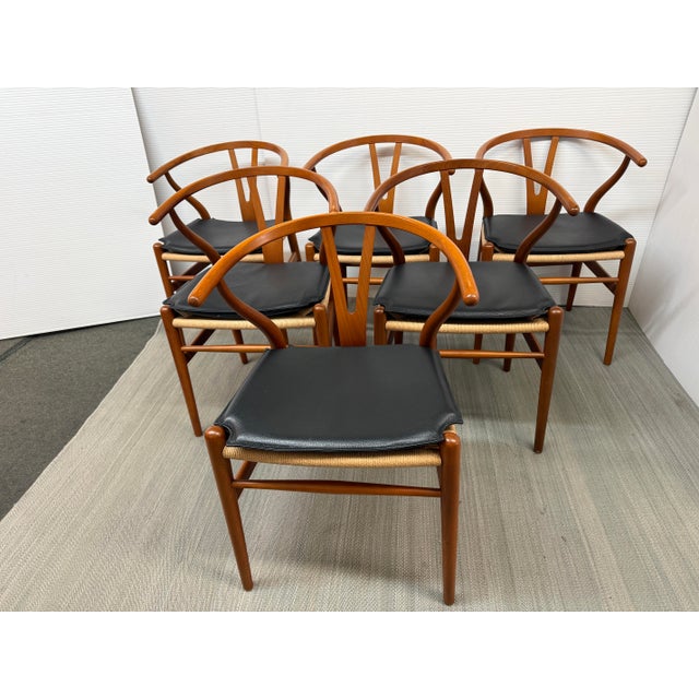 Design Plus Gallery presents a Set of Six Wishbone Chairs with Leather Seat Covers by Hans Wagner for Carl Hansen & Sons....