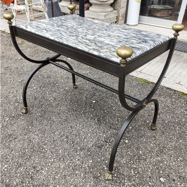 Wrought iron coffee table with brass feet in animal paw, brass knobs, black white speckled marble top, and gray ground on...