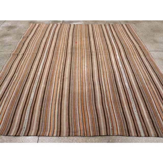 This Mid-20th century Turkish flatweave kilim rug, measuring 8' 0" x 8' 8", features a captivating striped design that...