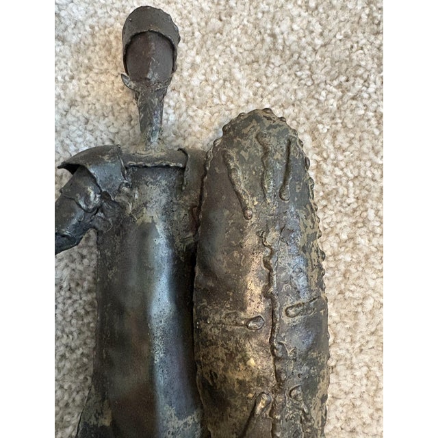 Vintage brutalist metal sculpture depicts the literary knight Don Quixote de la Mancha holding a long spear and shield....