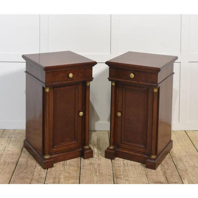A handsome pair of Empire-style bedside cabinets, finely crafted in rich mahogany with a warm polished finish. Each...