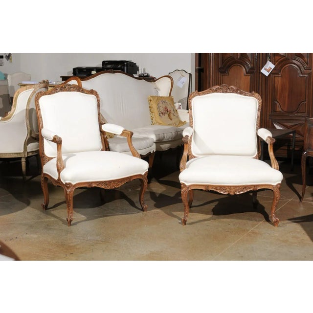 A pair of Italian Rococo style walnut armchairs from the 19th century, with carved skirts, cabriole legs and upholstery....