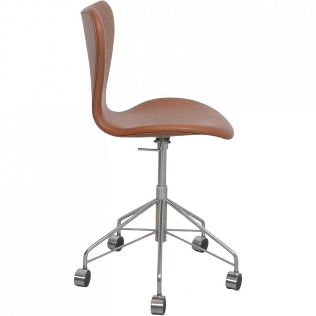 Arne Jacobsen 3117 office chair upholstered in cognac classic semi anilin leather, and with a chrome frame. The chair is...