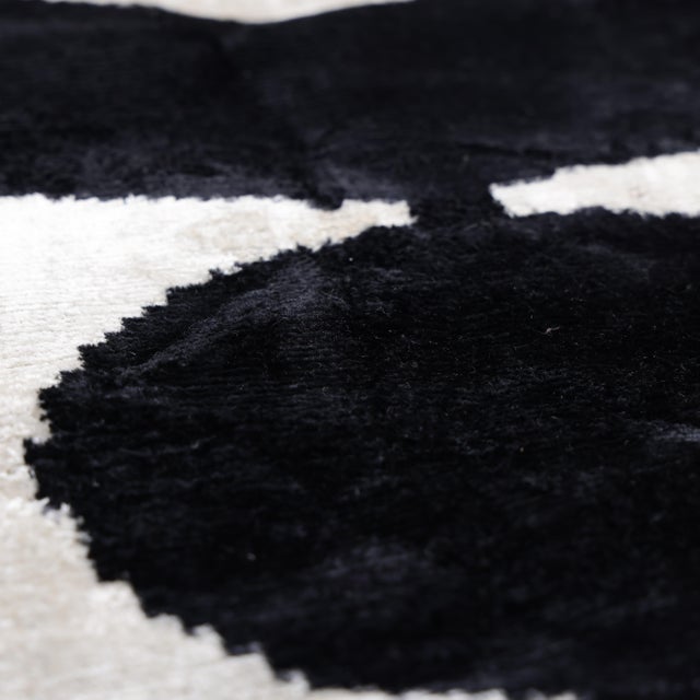 "A striking study in contrast and form, this handcrafted velvet pillow features bold black geometric shapes set against a...