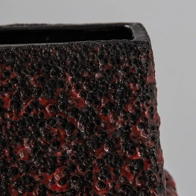 Encrusted with a tactile red glaze, carmine infused with sooty black recalls the heat of roiling lava. Frozen in motion,...