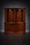 A monumental two-piece Baker Furniture bow front display cabinet featuring a dramatic convex form, dentil crown molding,...