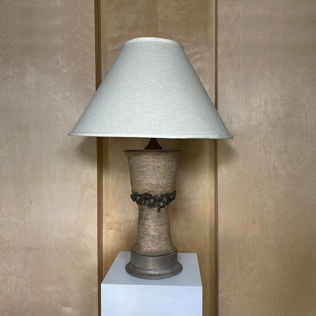 1970s ceramic table lamp with Medusa and Serpent details. Linen shade. Overall dimensions: 23" Diameter x 32"H. Shade...