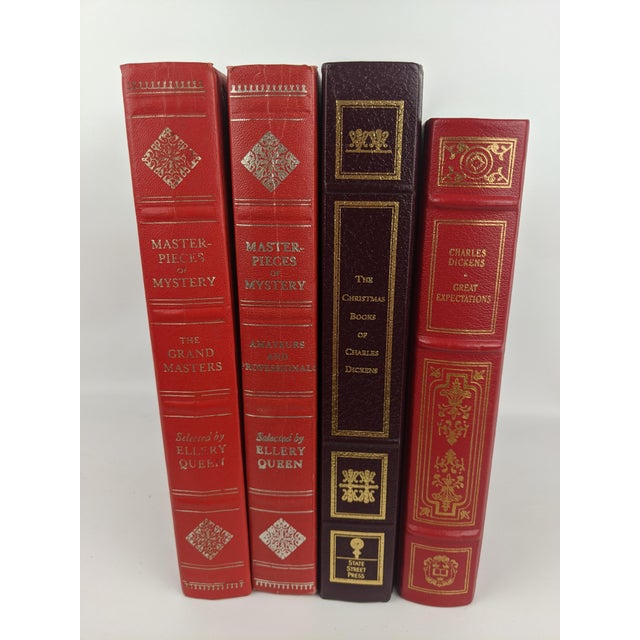 Striking collection of four decorative hardcover volumes in rich shades of red and burgundy, unified by elaborate gold and...