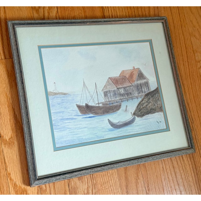 Charming 1990s folk art coastal seascape watercolor with nautical motifs of sailboats, a boathouse, and a distant...