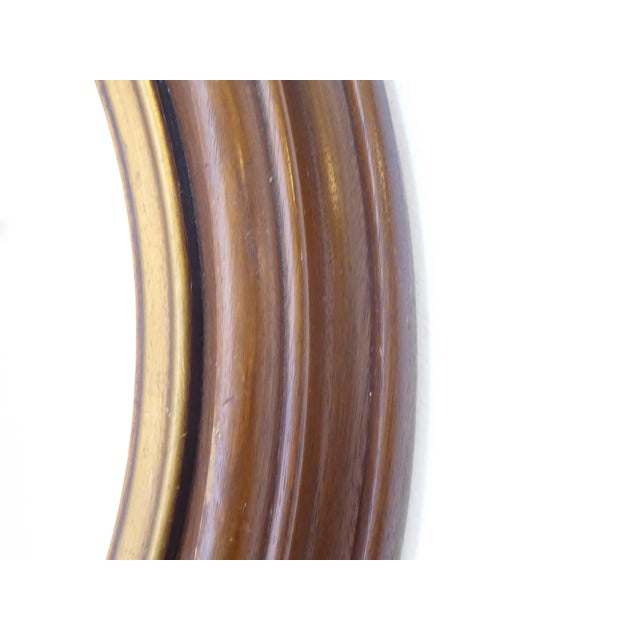 This solid walnut American early 20th Century mirror with giltwood inner edging, measures 21" Diameter by 2" Deep.