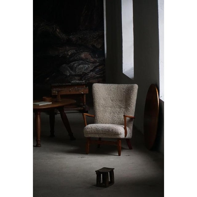 Presenting a charming high back lounge chair from the 1950s, crafted in solid oak and thoughtfully reupholstered in a...